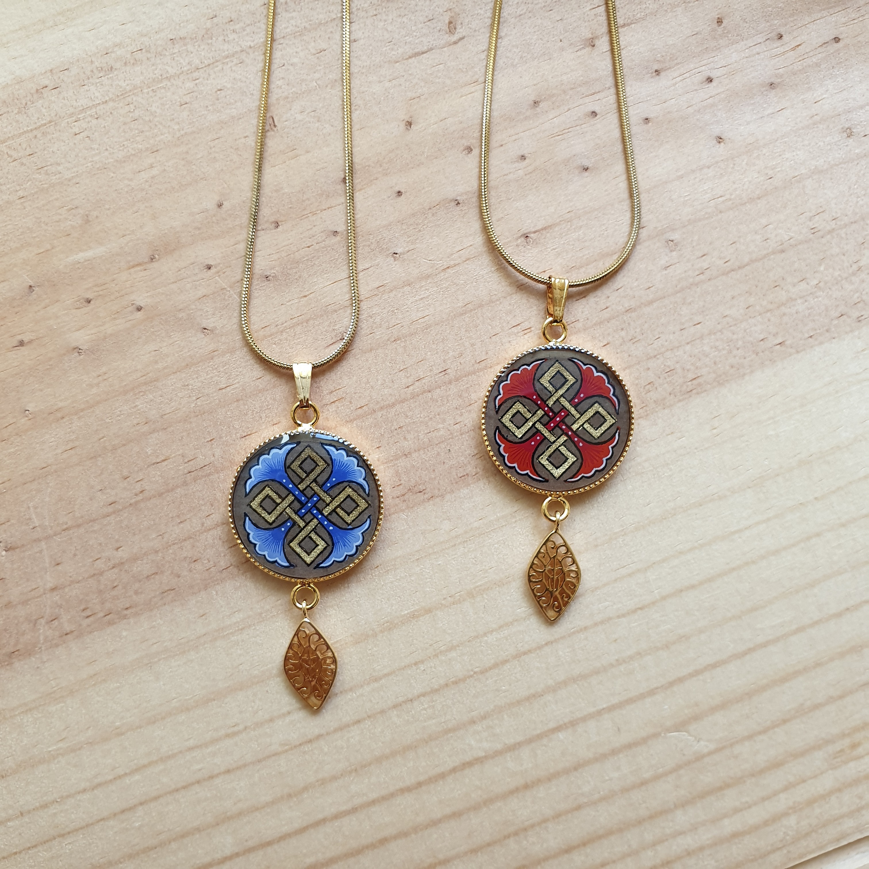 Colliers pendentifs dorés avec motifs palmettes et entrelacs colorés.