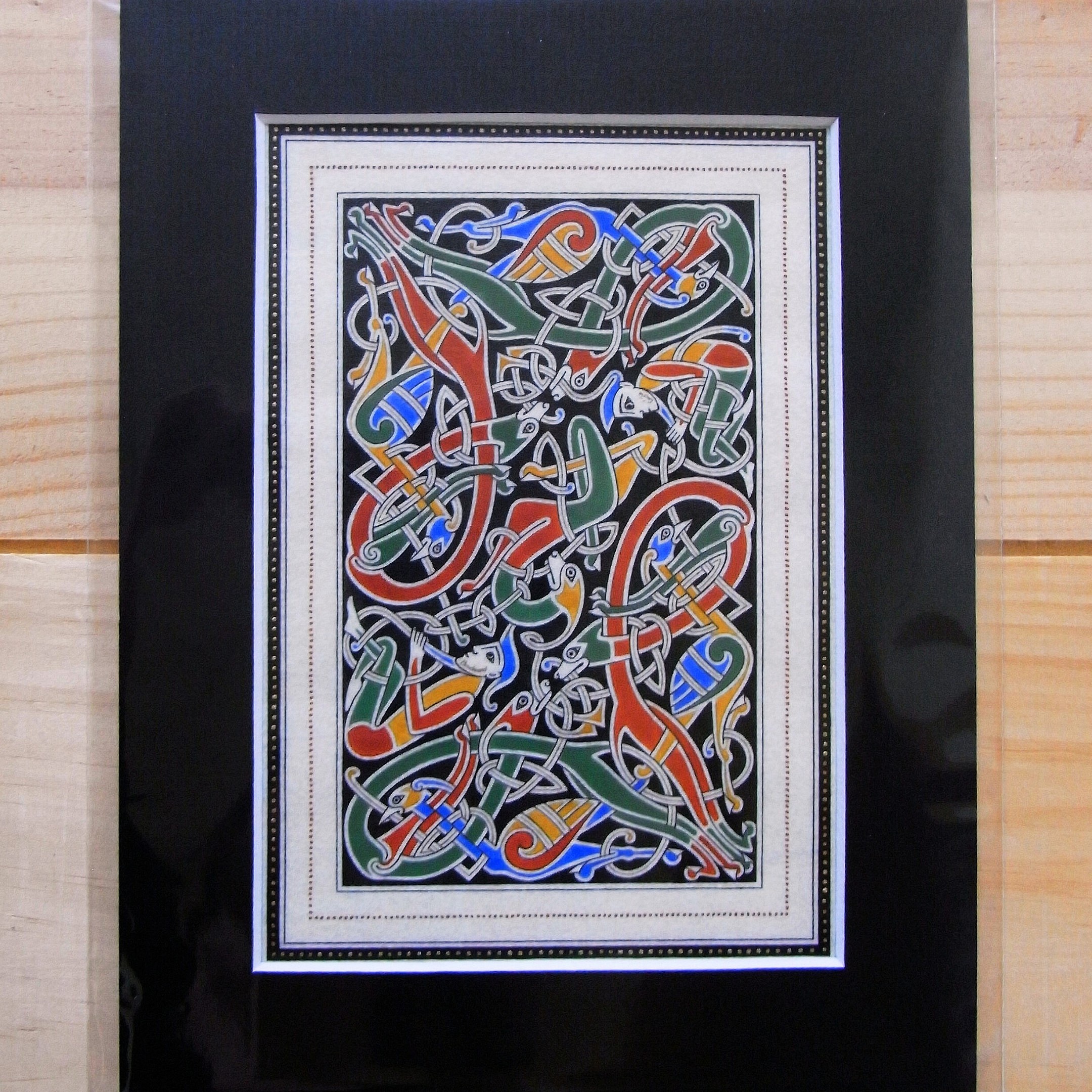 Enluminure insulaire aux entrelacs zoomorphes sur fond noir.